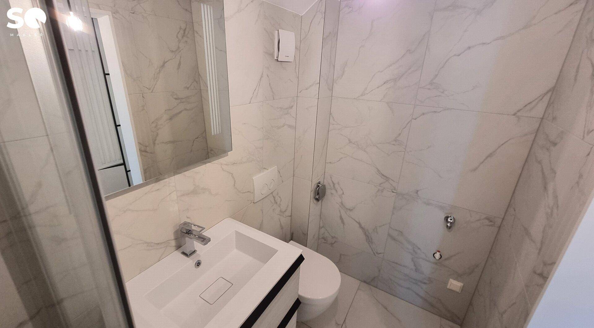 Modernes Badezimmer mit Marmorfliesen, wandhängendem WC und elegantem Waschtisch mit Spiegelschrank.