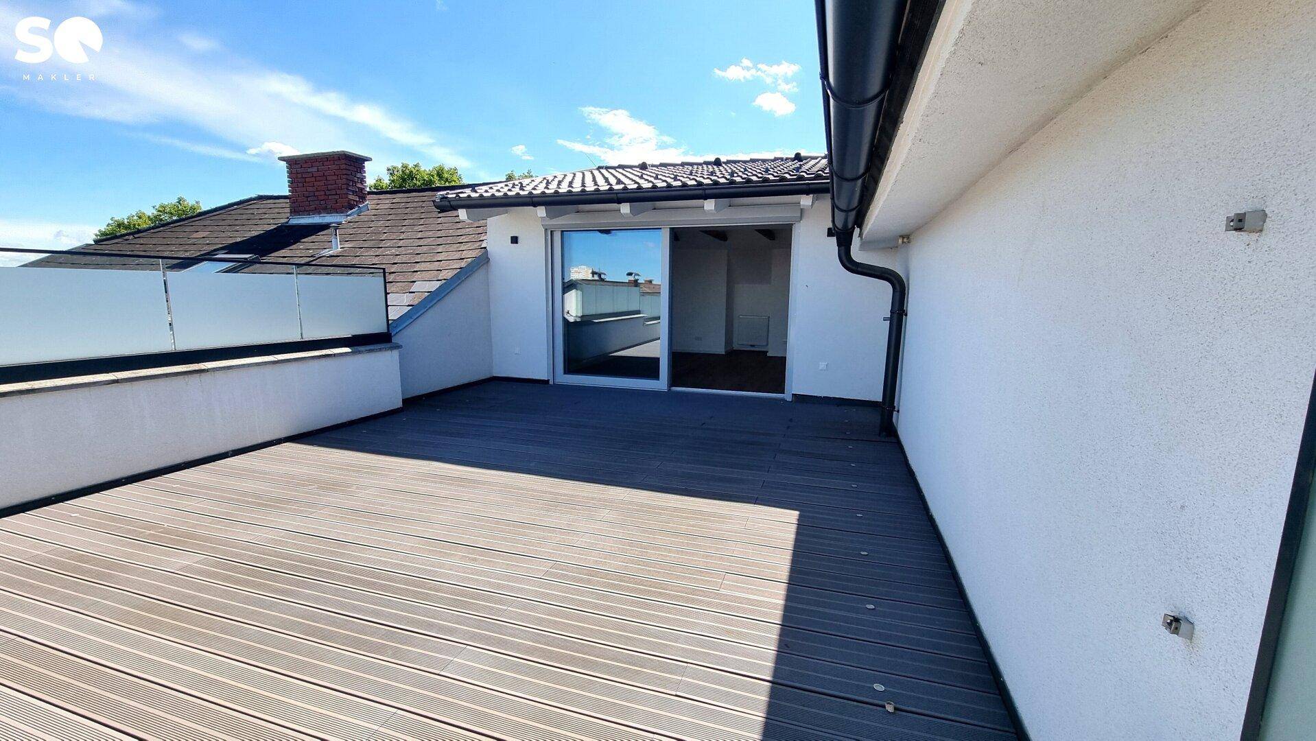 Sonnige Dachterrasse mit Holzdielenboden und Glasgeländer, direkt am Haus gelegen.