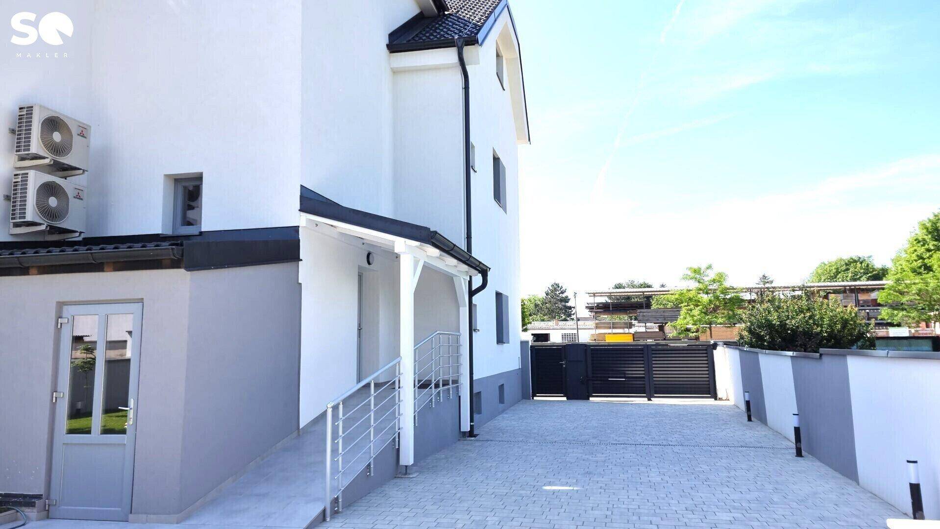 Eingangsbereich des Hauses mit Rampe, Geländer und gepflasterter Zufahrt.