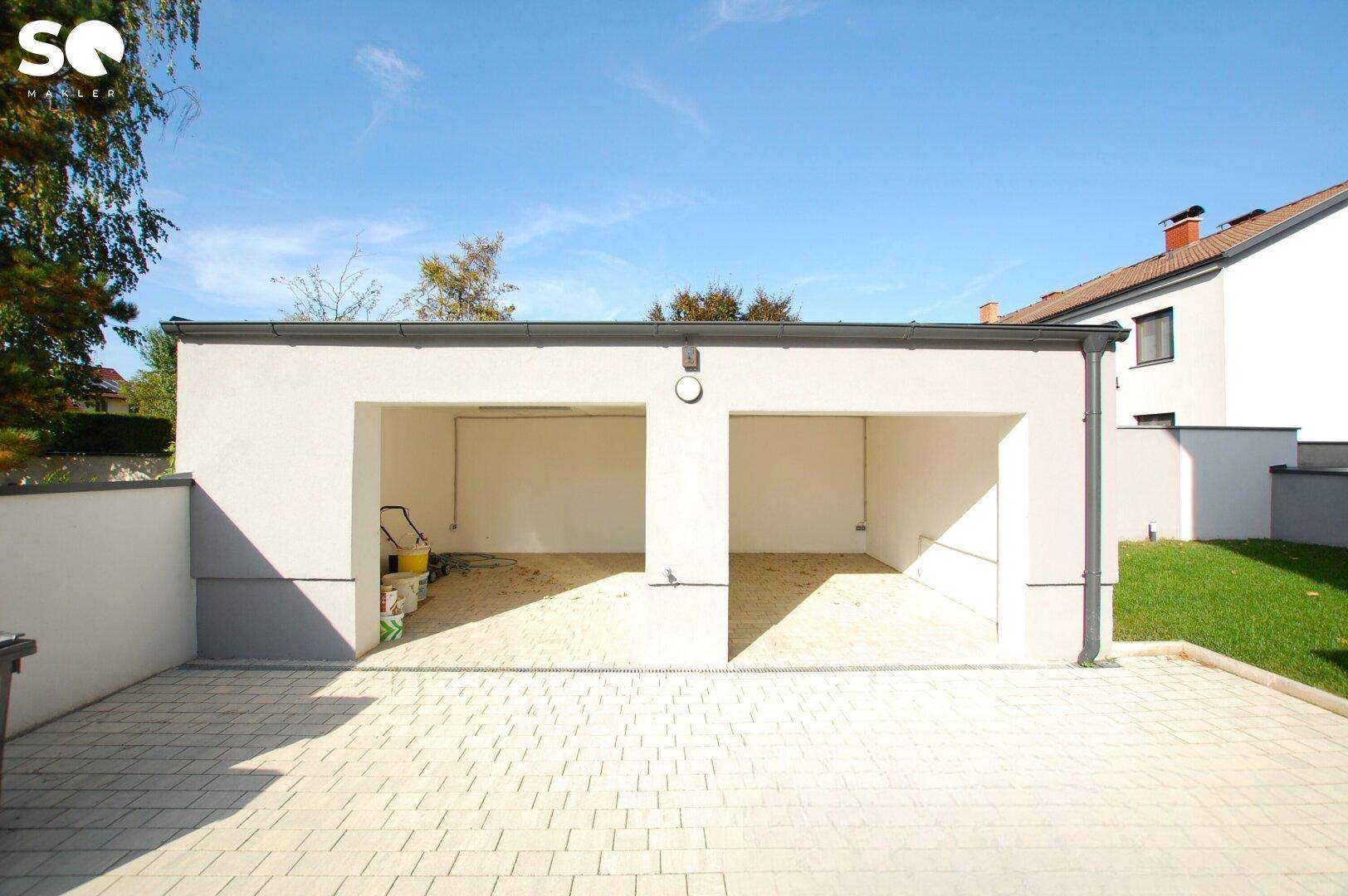 Doppelgarage mit zwei offenen Stellplätzen und gepflasterter Zufahrt.