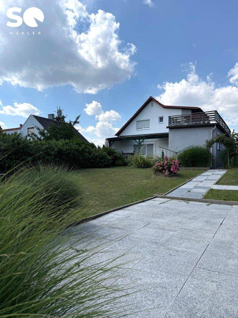 Großer Garten mit Rasenfläche, gepflastertem Weg und Blick auf das Haus.