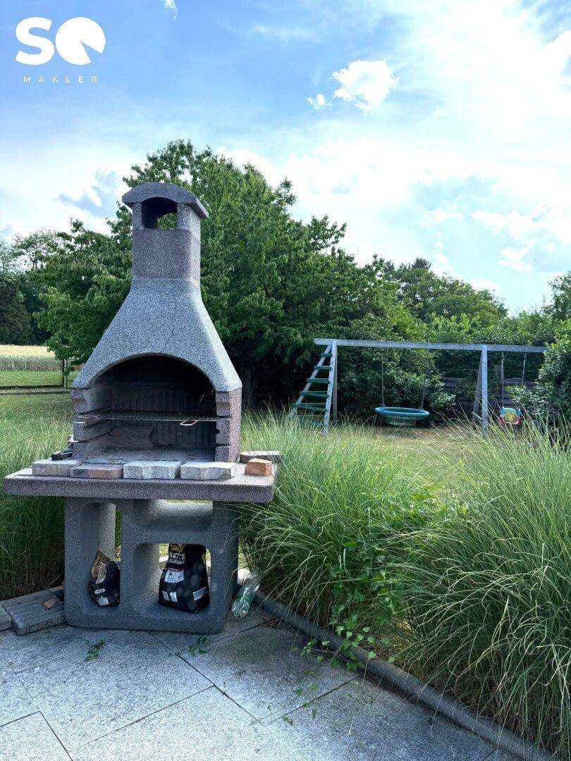 Gemauerter Grillplatz und Kinderspielplatz im weitläufigen Garten.