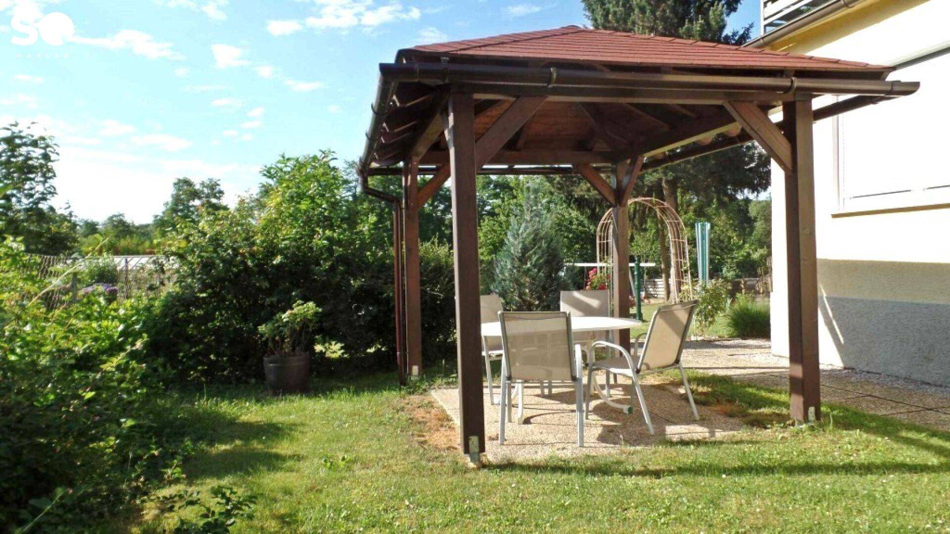Gemütliche Gartenlaube mit Sitzgelegenheiten auf der Rasenfläche.