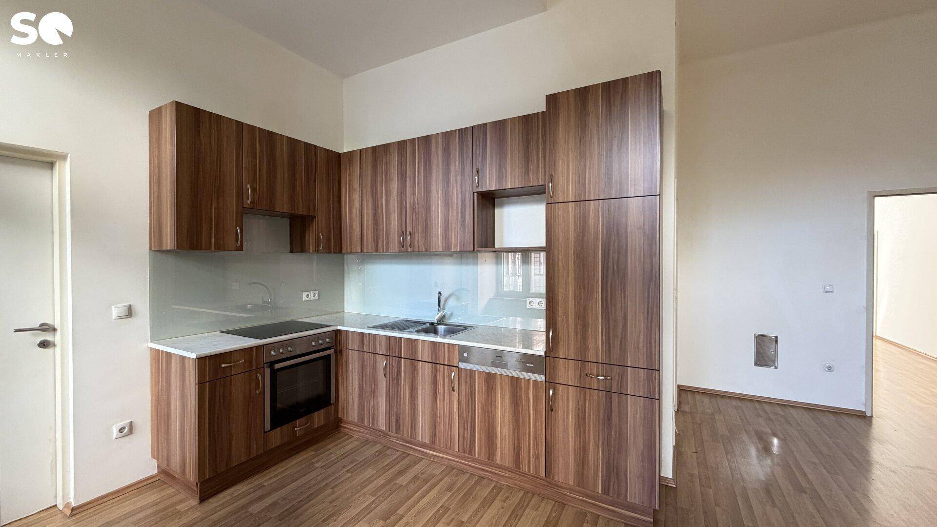 Funktionale Einbauküche mit Holzfronten, modernen Geräten und heller Arbeitsplatte.