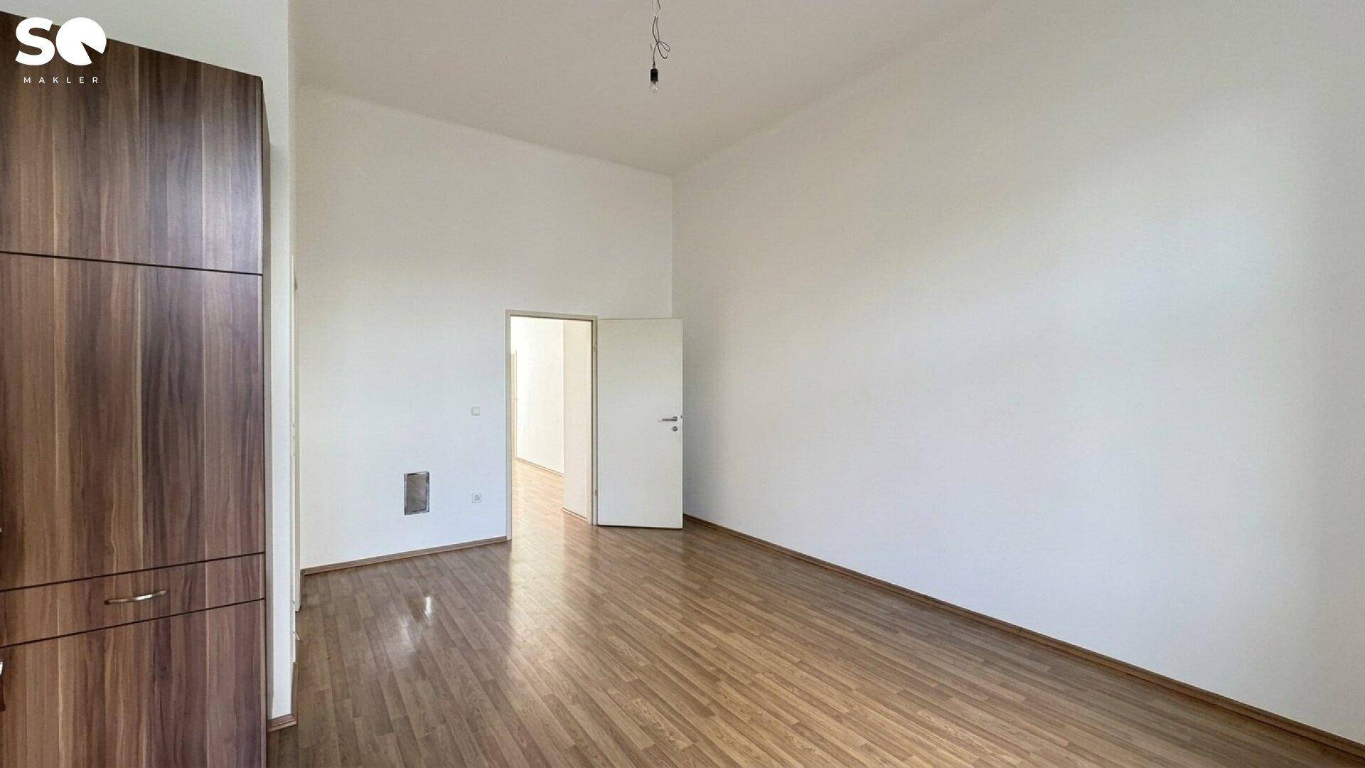 Leerer Raum mit Holzparkettboden und weißen Wänden, ideal für individuelle Einrichtung.