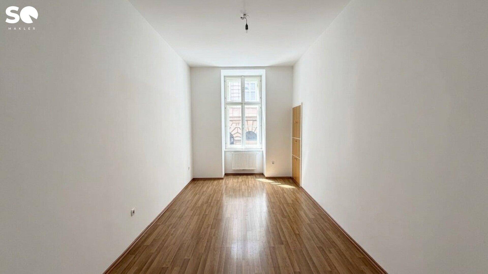 Ruhiges Schlafzimmer mit Parkettboden und einem großen Fenster, ideal für Erholung.