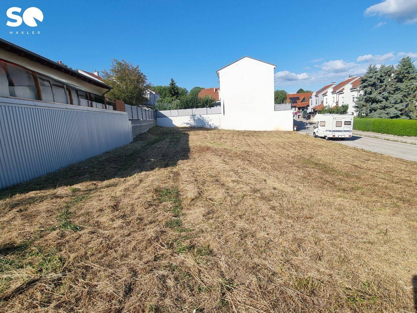 Sonnenbeschienenes Grundstück mit Blick auf die Straße und umliegende Wohnhäuser.