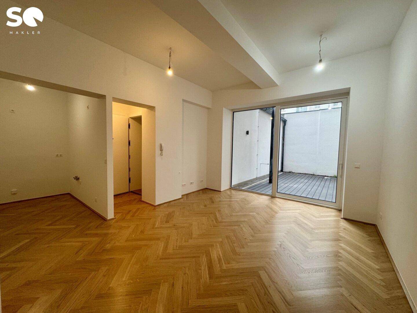 Heller Wohnraum mit Fischgrätparkett und großem Schiebetürzugang zur Terrasse.