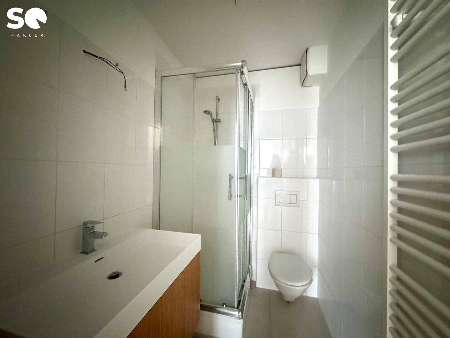 Modernes Badezimmer mit Duschkabine, wandhängendem WC und Handtuchheizkörper.