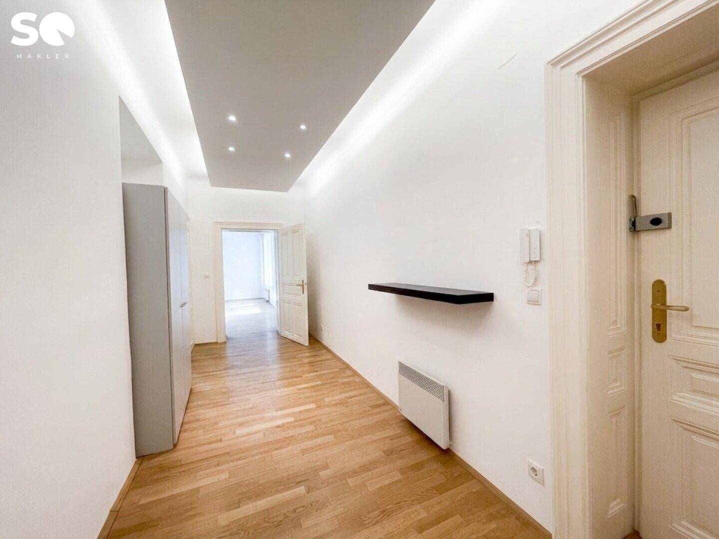 Heller Flur mit Holzparkettboden, moderner Deckenbeleuchtung und einer schwebenden Ablage an der Wand.