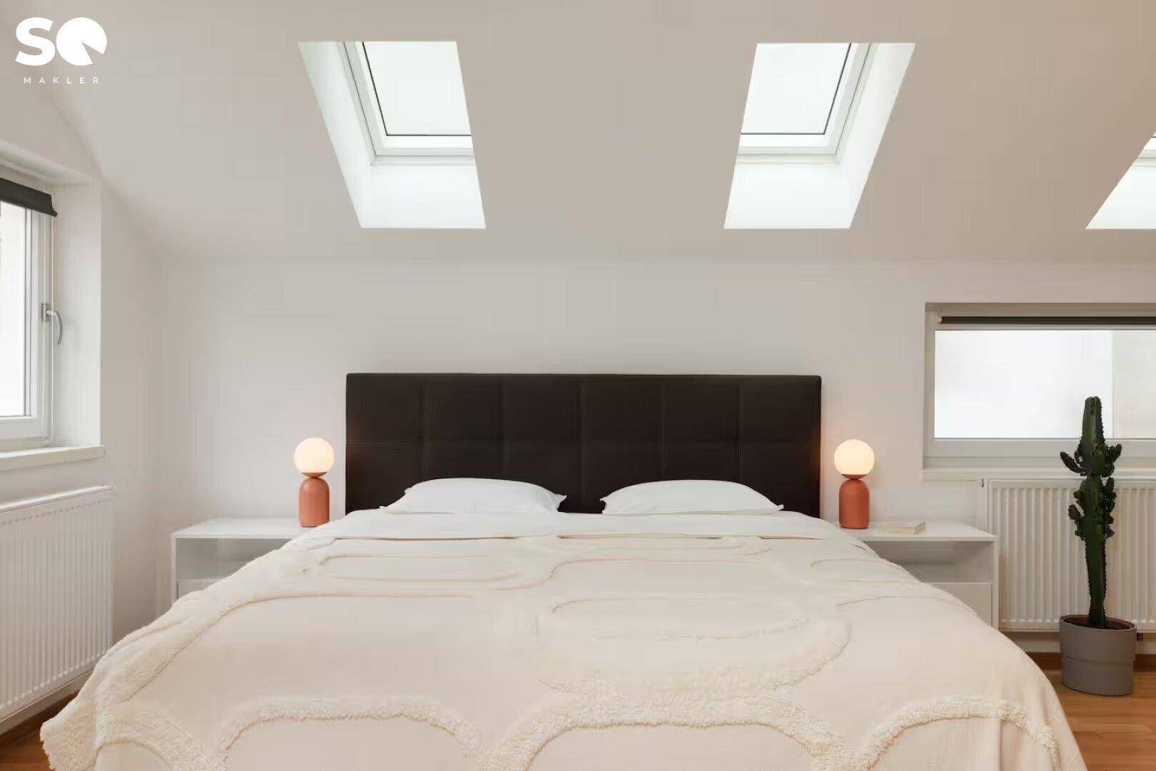 Gemütliches Doppelbett mit gepolstertem Kopfteil und zwei Dachfenstern für viel Tageslicht.