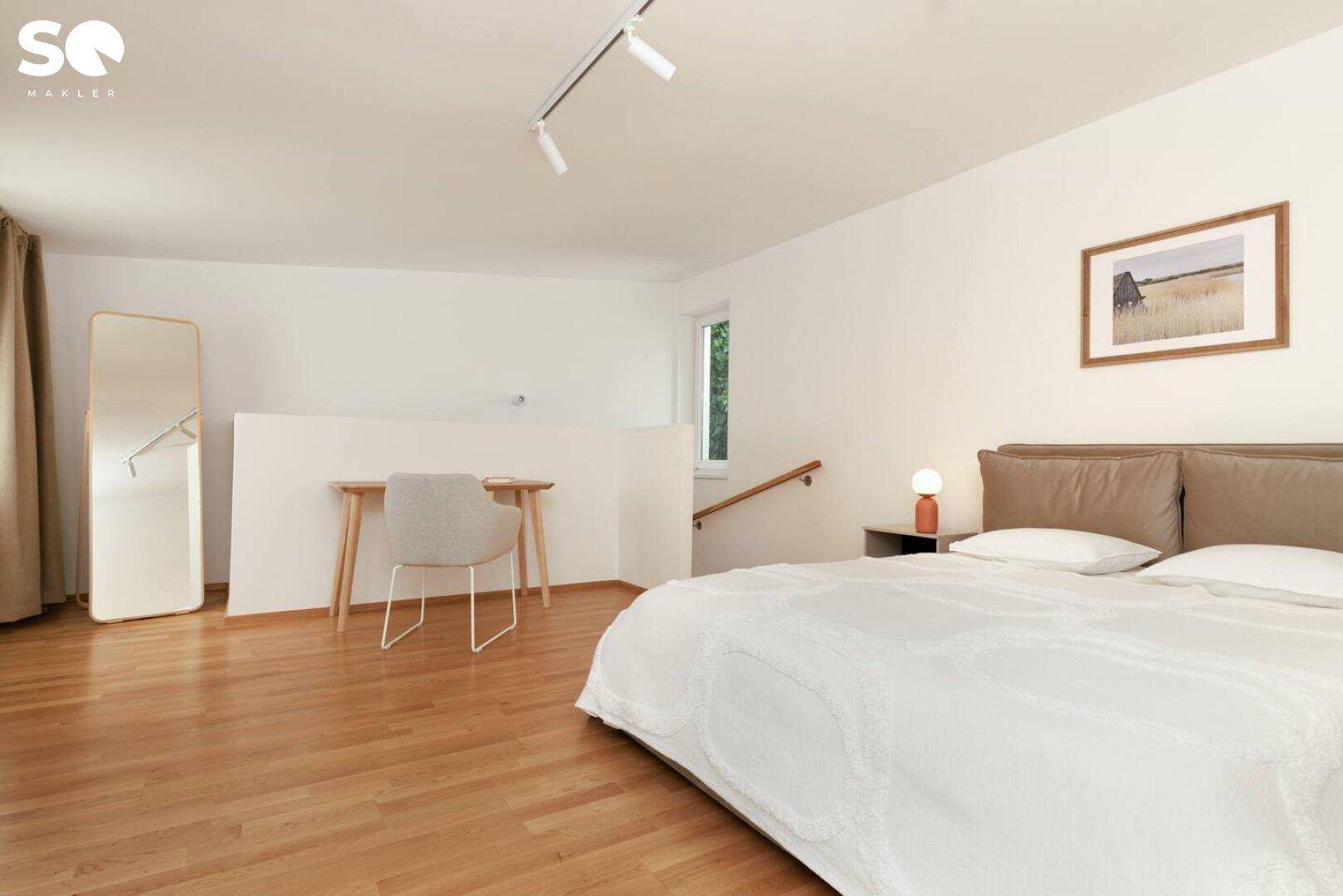 Geräumiges Schlafzimmer mit Doppelbett, Schreibtisch und Holzfußboden.