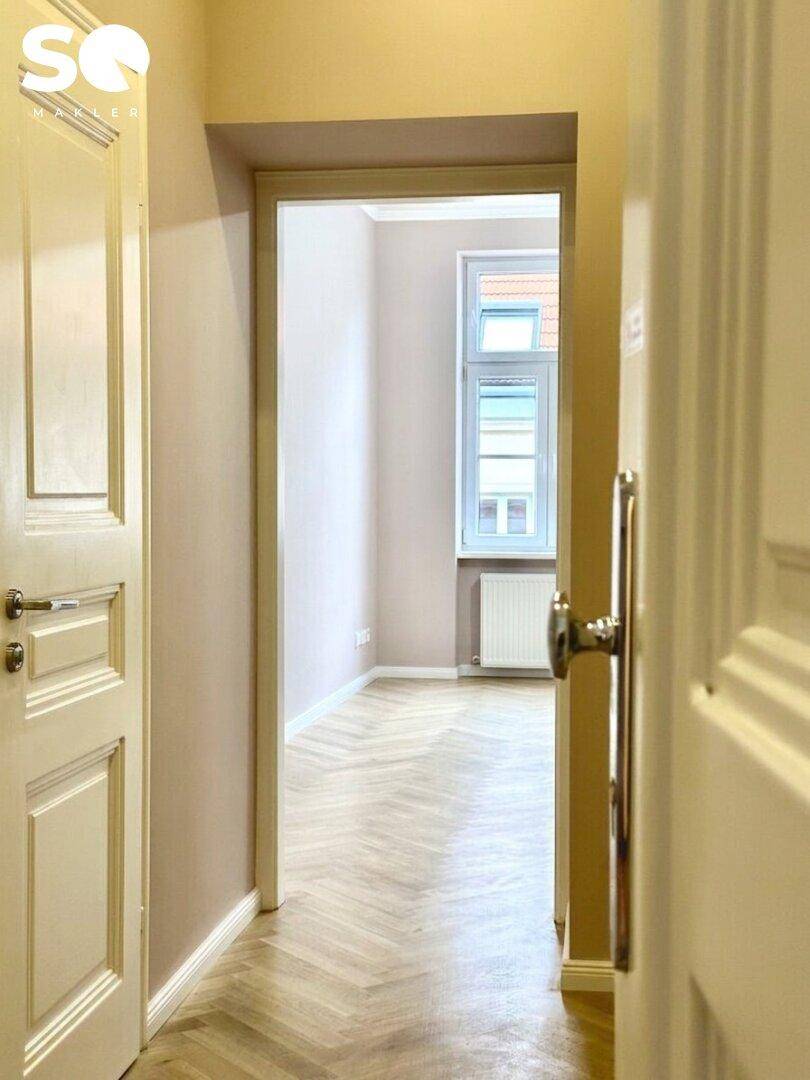 Heller Flur mit Fischgrätparkett und Blick in angrenzende Zimmer.