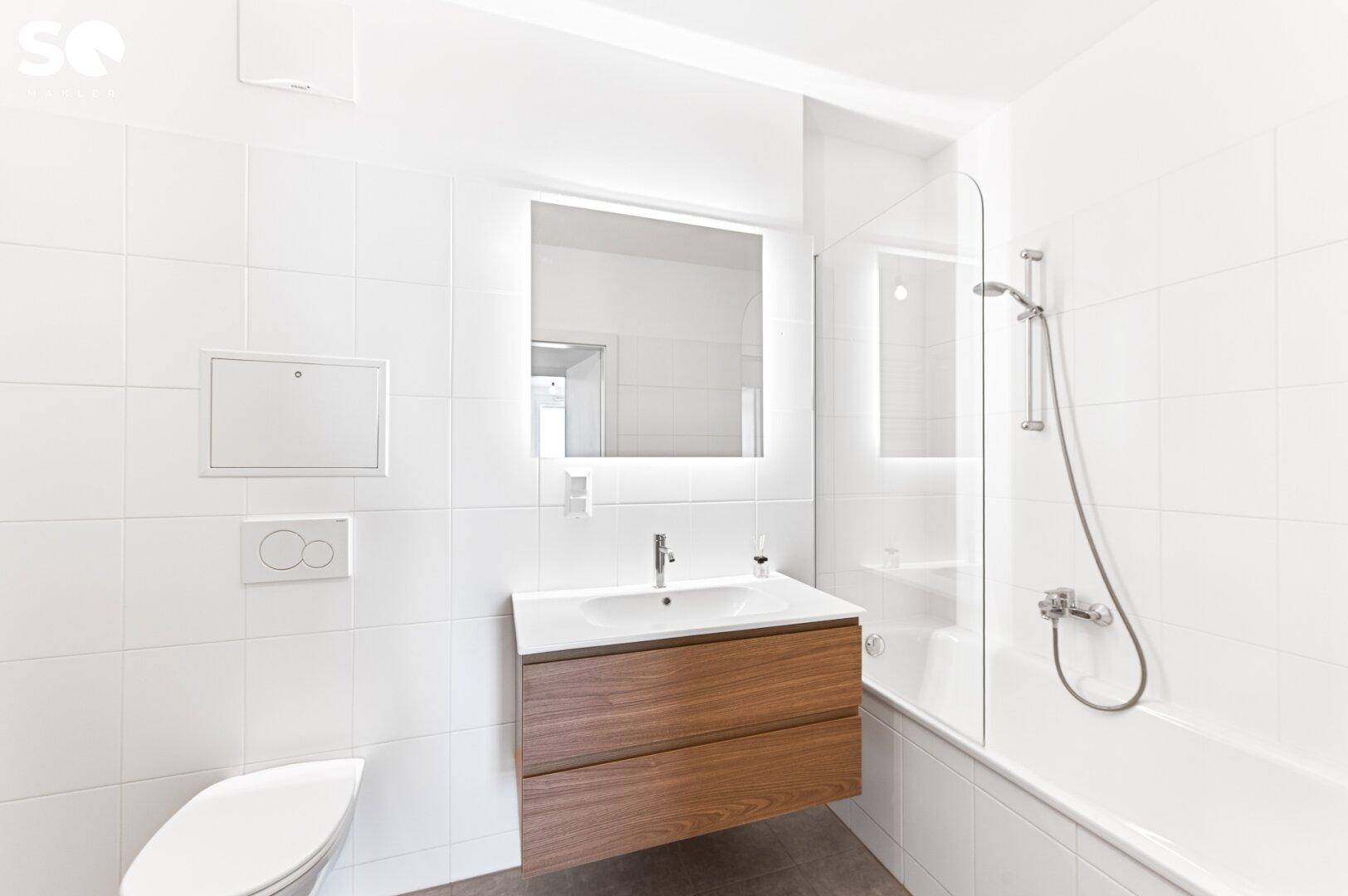 Helles Badezimmer mit Badewanne, modernem Waschtisch und Wand-WC.