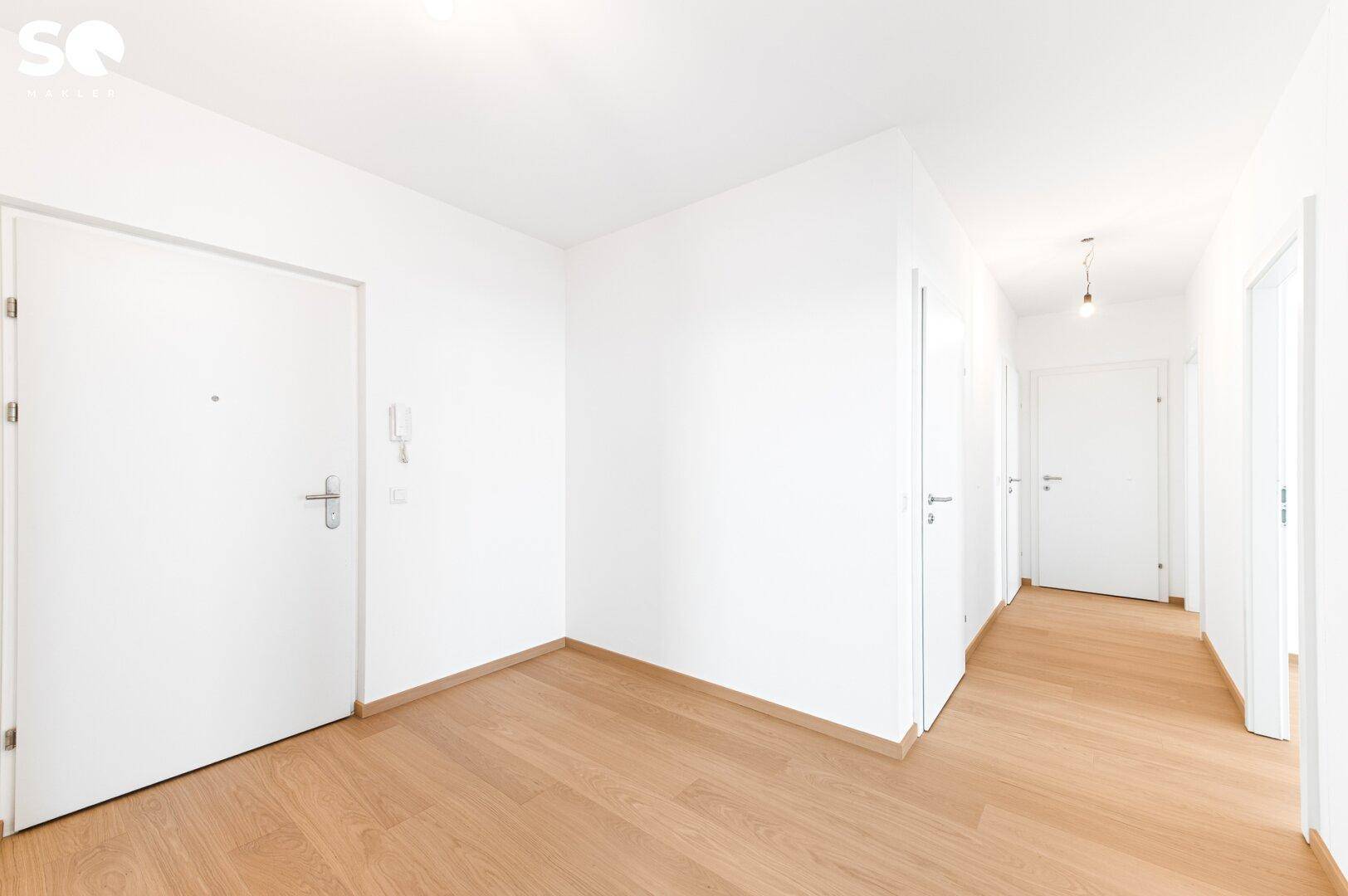 Heller Eingangsbereich mit Holzparkettboden und Zugang zu verschiedenen Räumen.