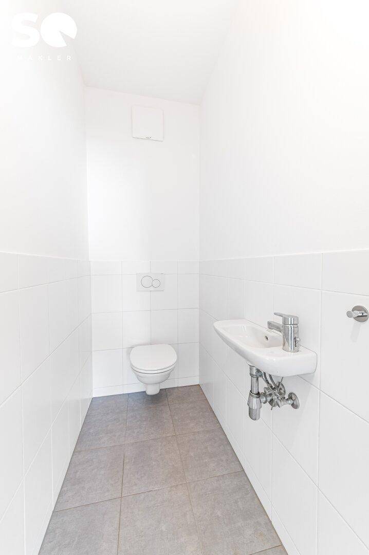 Separates Gäste-WC mit Wand-WC und kleinem Handwaschbecken.