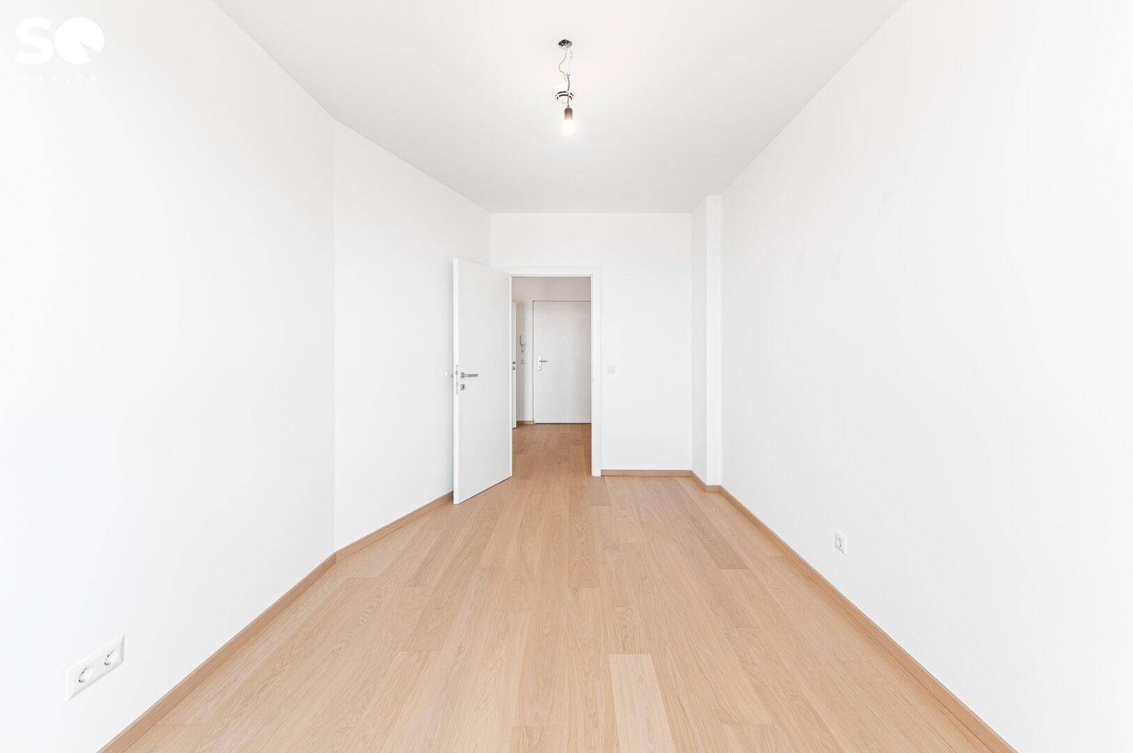 Leeres Zimmer mit hellem Holzboden und weißen Wänden, bereit zur individuellen Gestaltung.