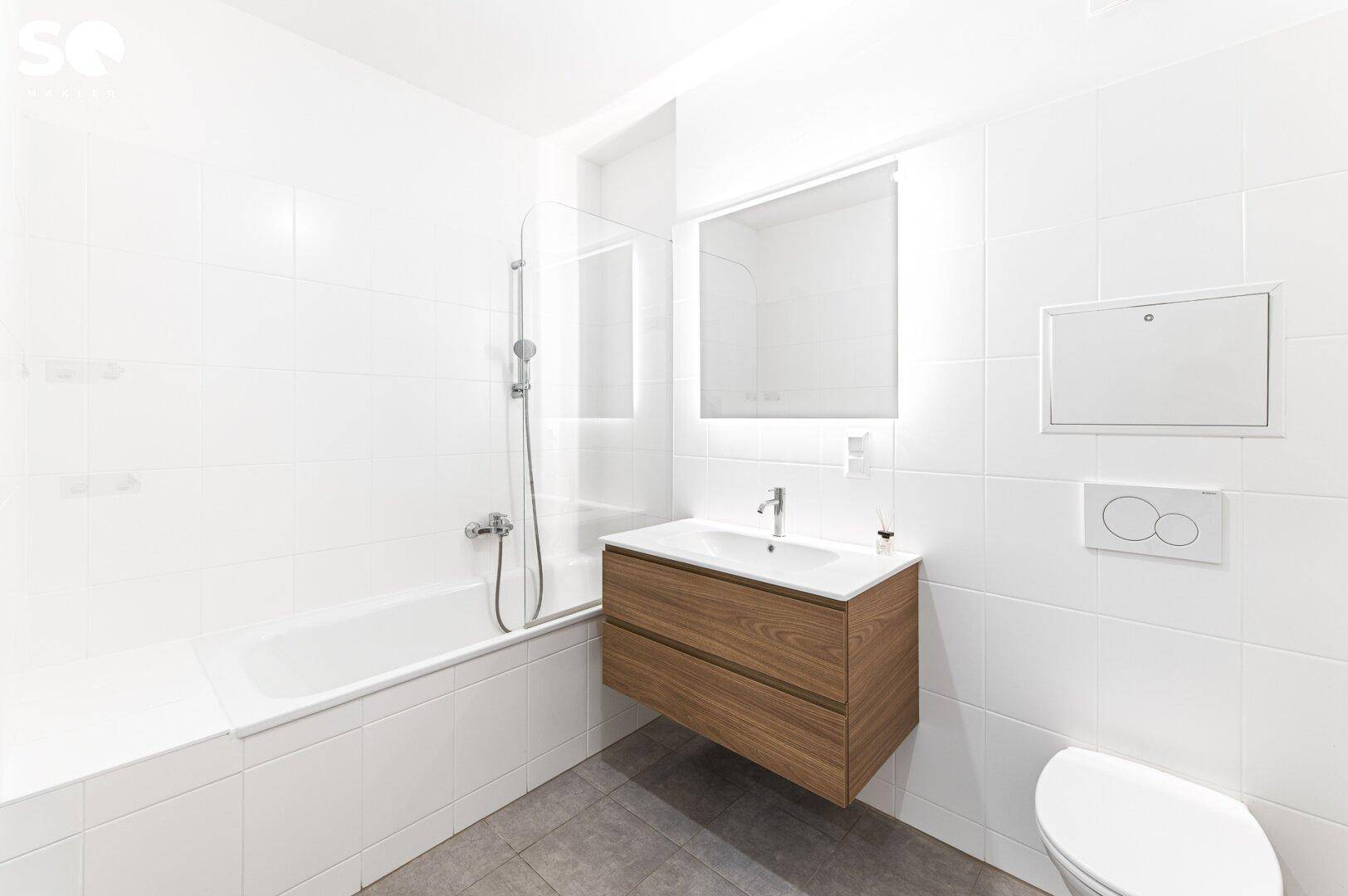 Modernes Badezimmer mit Badewanne, Duschfunktion, Waschbecken und weißen Fliesen.