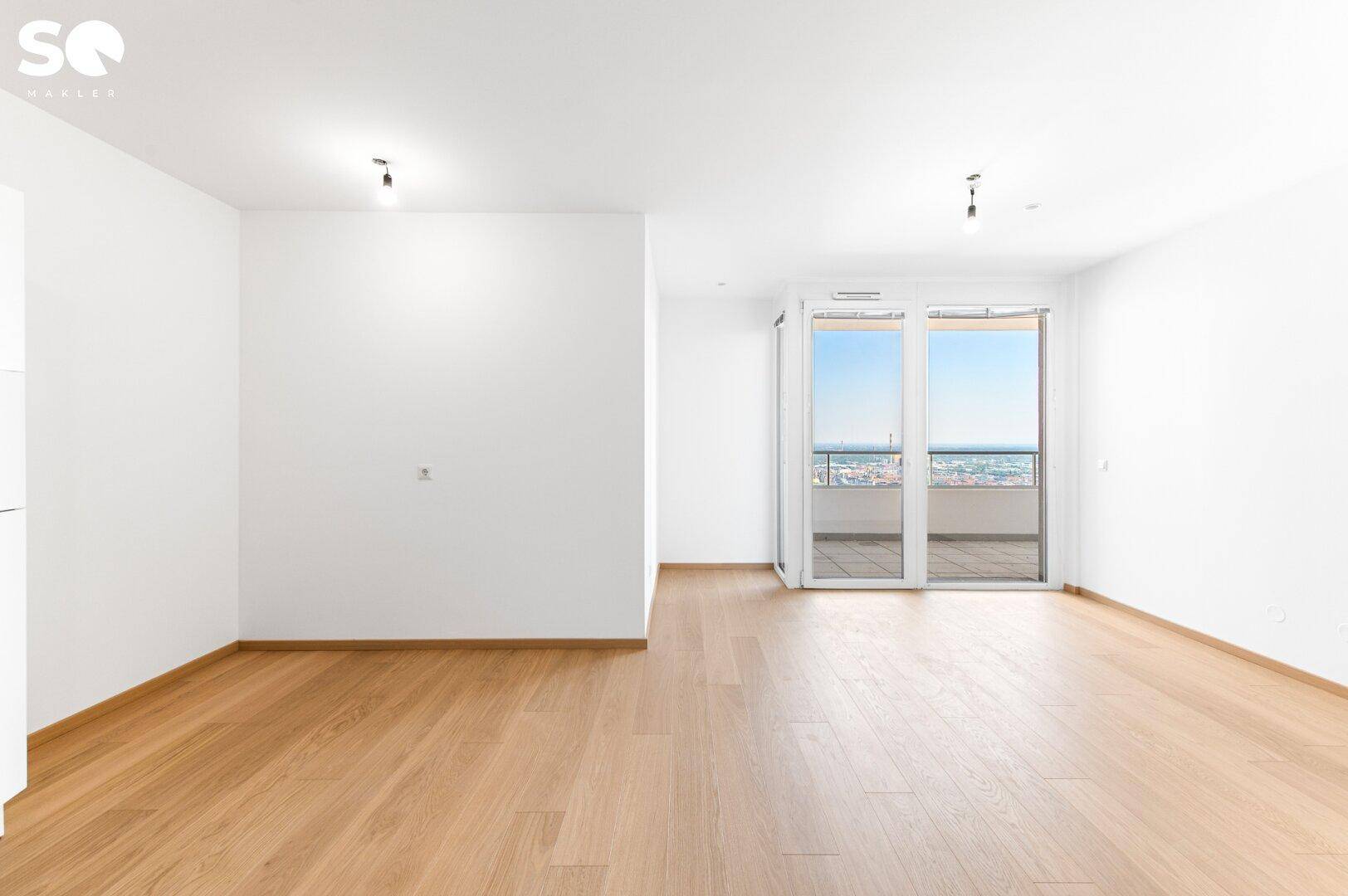 Geräumiges, helles Wohnzimmer mit Parkettboden und Zugang zum Balkon mit Stadtblick.