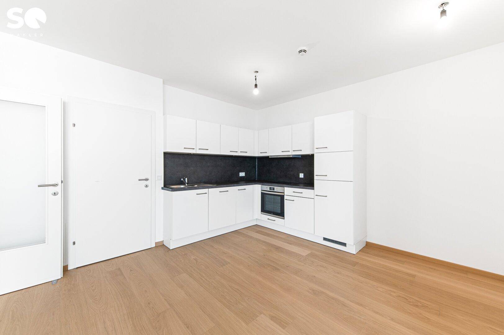 Moderne, weiße Einbauküche mit dunkler Arbeitsplatte und integriertem Backofen.