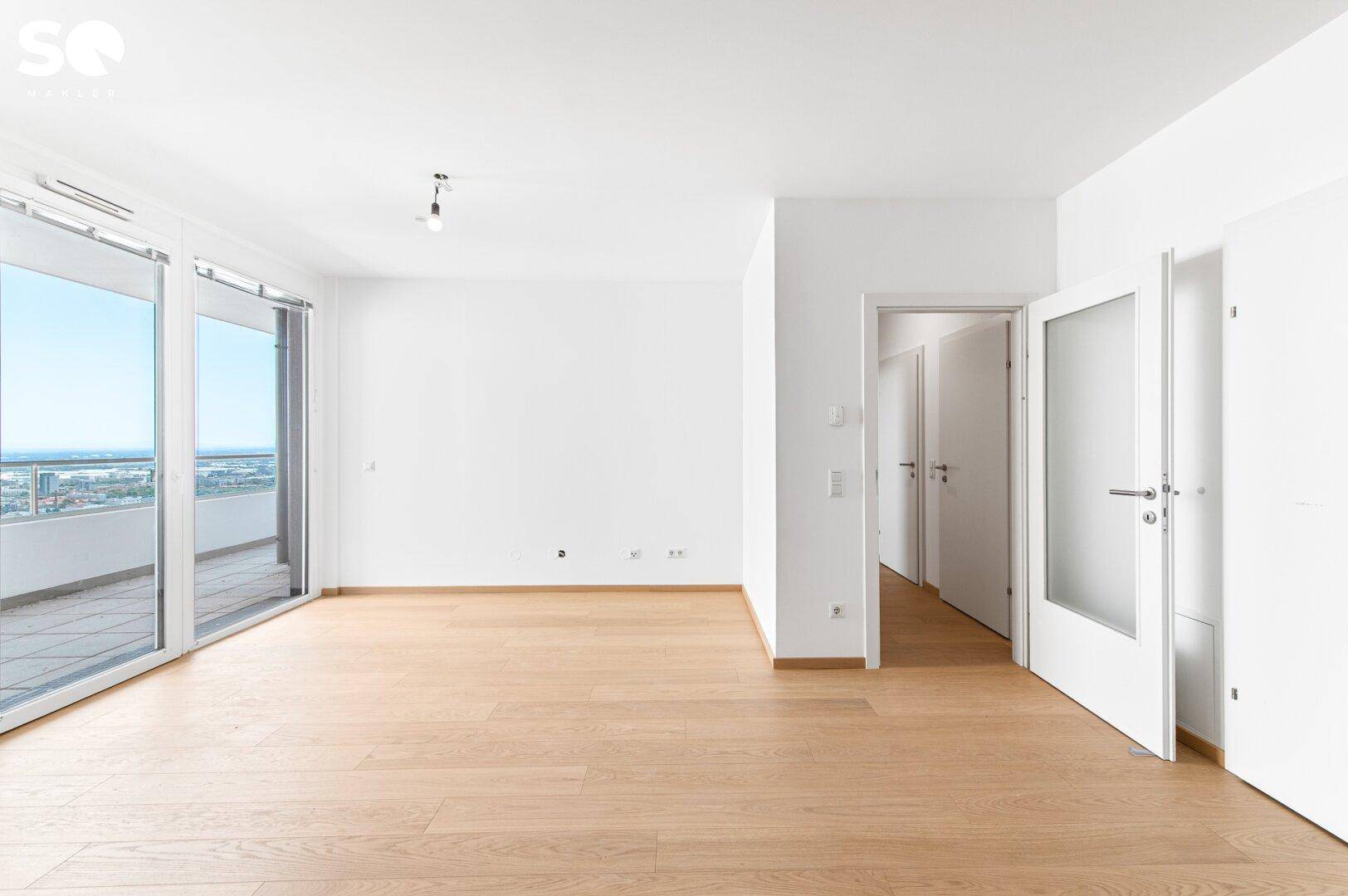 Helles Wohnzimmer mit Parkettboden und großen Fenstern, die Zugang zum Balkon bieten.