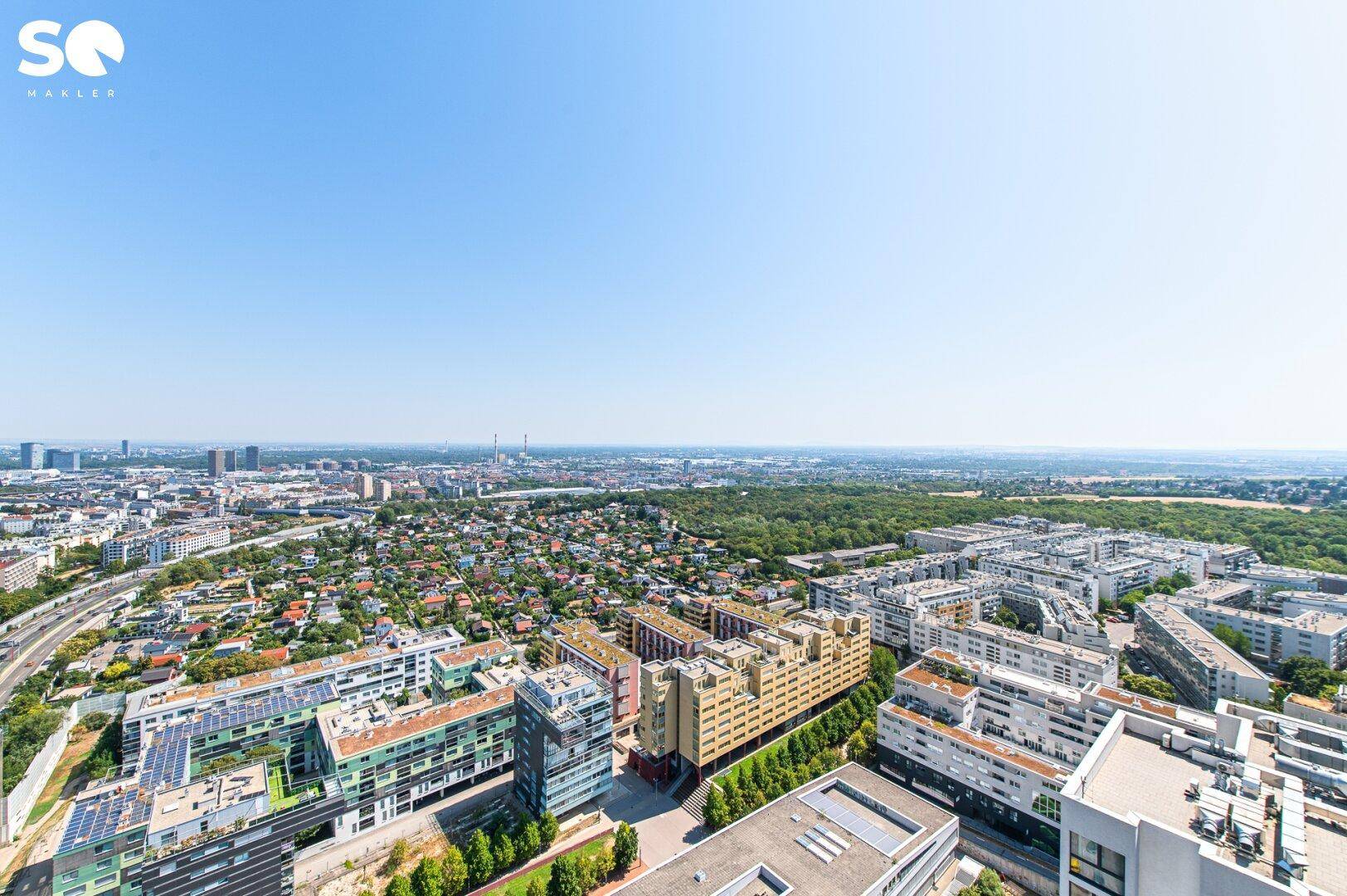 Panoramablick über die Stadt mit Wohngebäuden, Grünflächen und Autobahn.
