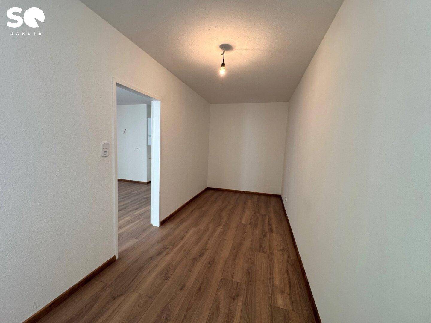 Kleiner, heller Raum mit Laminatboden und weiß gestrichenen Wänden, ideal als Arbeitszimmer.