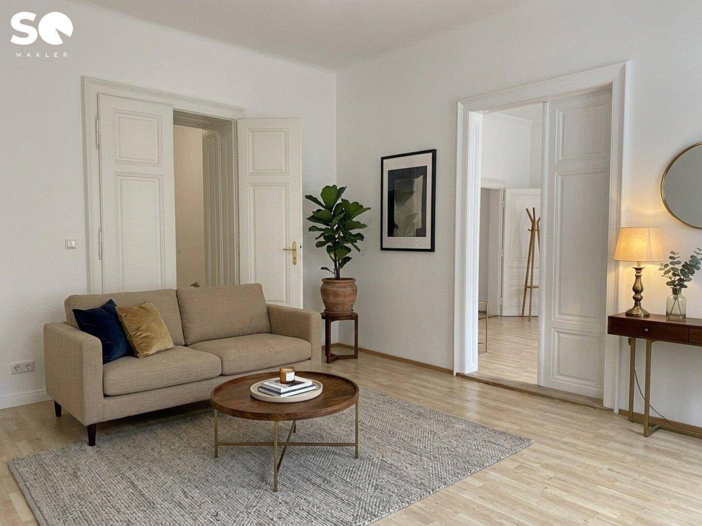 Gemütliches Wohnzimmer mit beigem Sofa, Holzboden und stilvoller Dekoration.