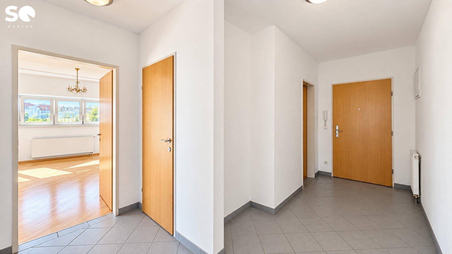 Heller Flur mit Fliesenboden und Zugang zu verschiedenen Räumen.