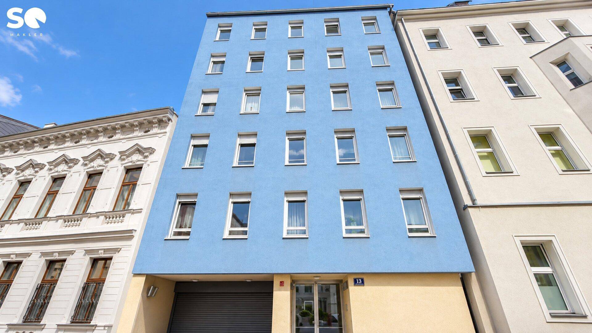Moderne Fassade eines Mehrfamilienhauses in leuchtendem Blau mit vielen Fenstern.
