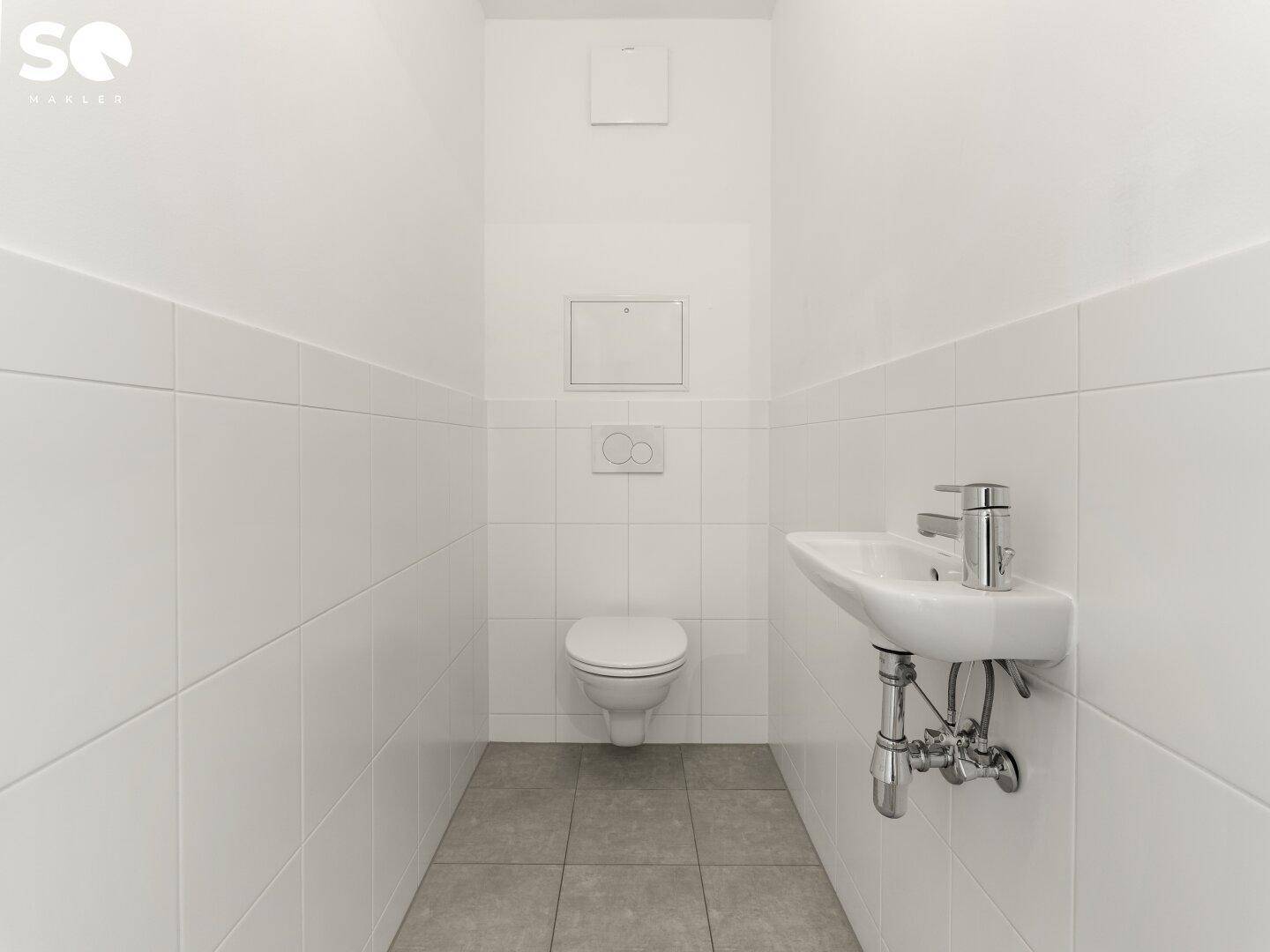 Kleines Gäste-WC mit weißen Fliesen, wandhängendem WC und Handwaschbecken.