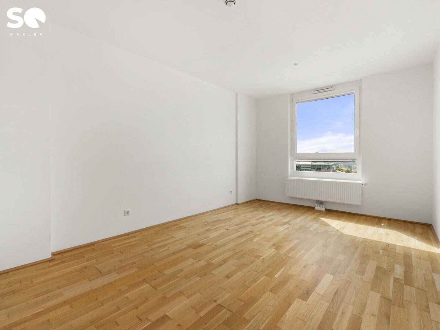 Heller Raum mit Parkettboden und großem Fenster, geeignet als Schlaf- oder Arbeitszimmer.
