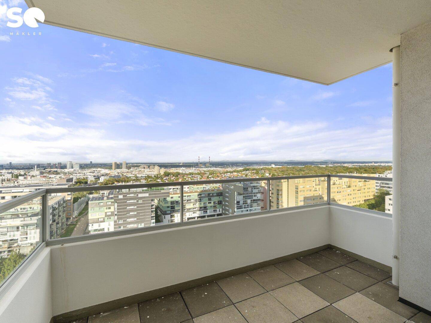 Geräumiger Balkon mit Glasgeländer und weitem Blick über die Stadtlandschaft.