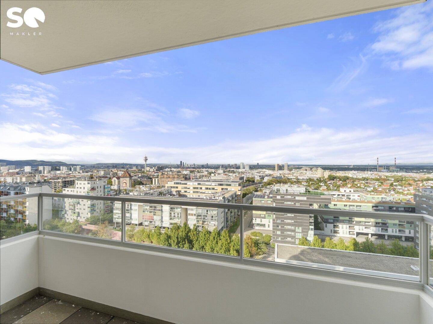 Geräumiger Balkon mit Glasgeländer und weitem Blick über die Stadtlandschaft.