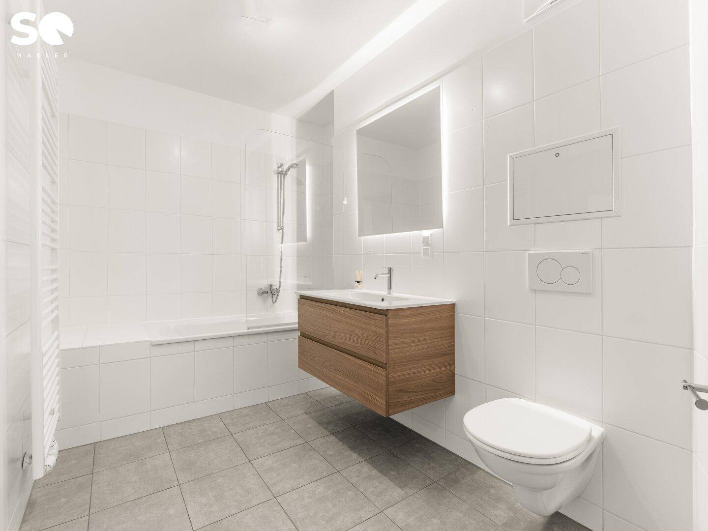 Modernes Badezimmer mit weißen Fliesen, Badewanne und schwebendem Waschtisch.