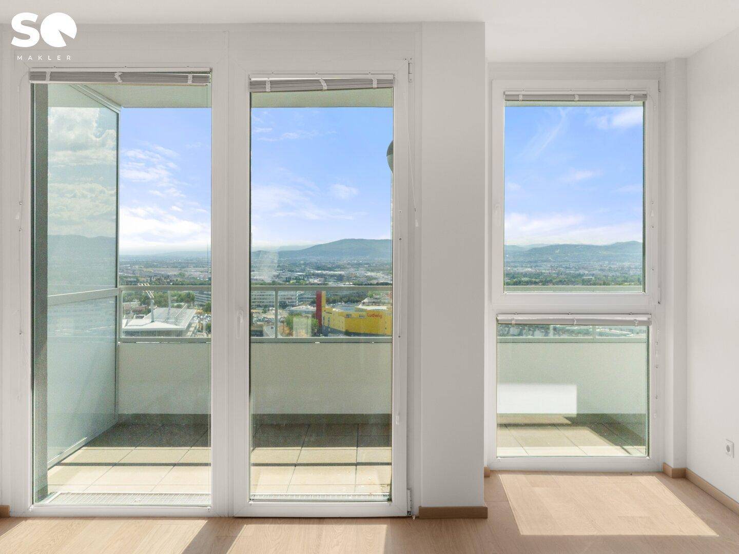 Heller Raum mit großen Fenstern und Balkonzugang, bietet weite Aussicht.