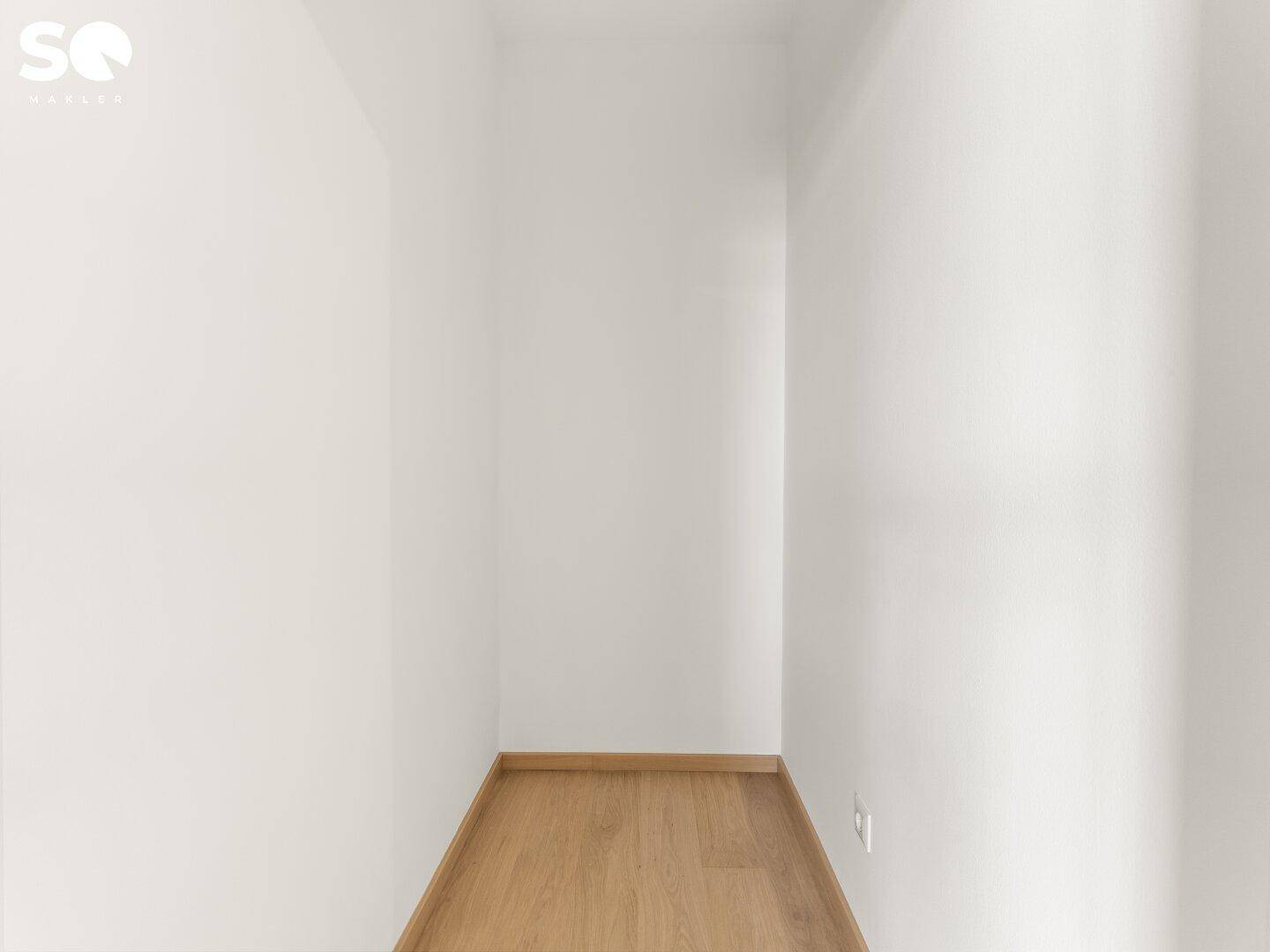 Kleiner, leerer Abstellraum mit hellem Holzboden und weißen Wänden.
