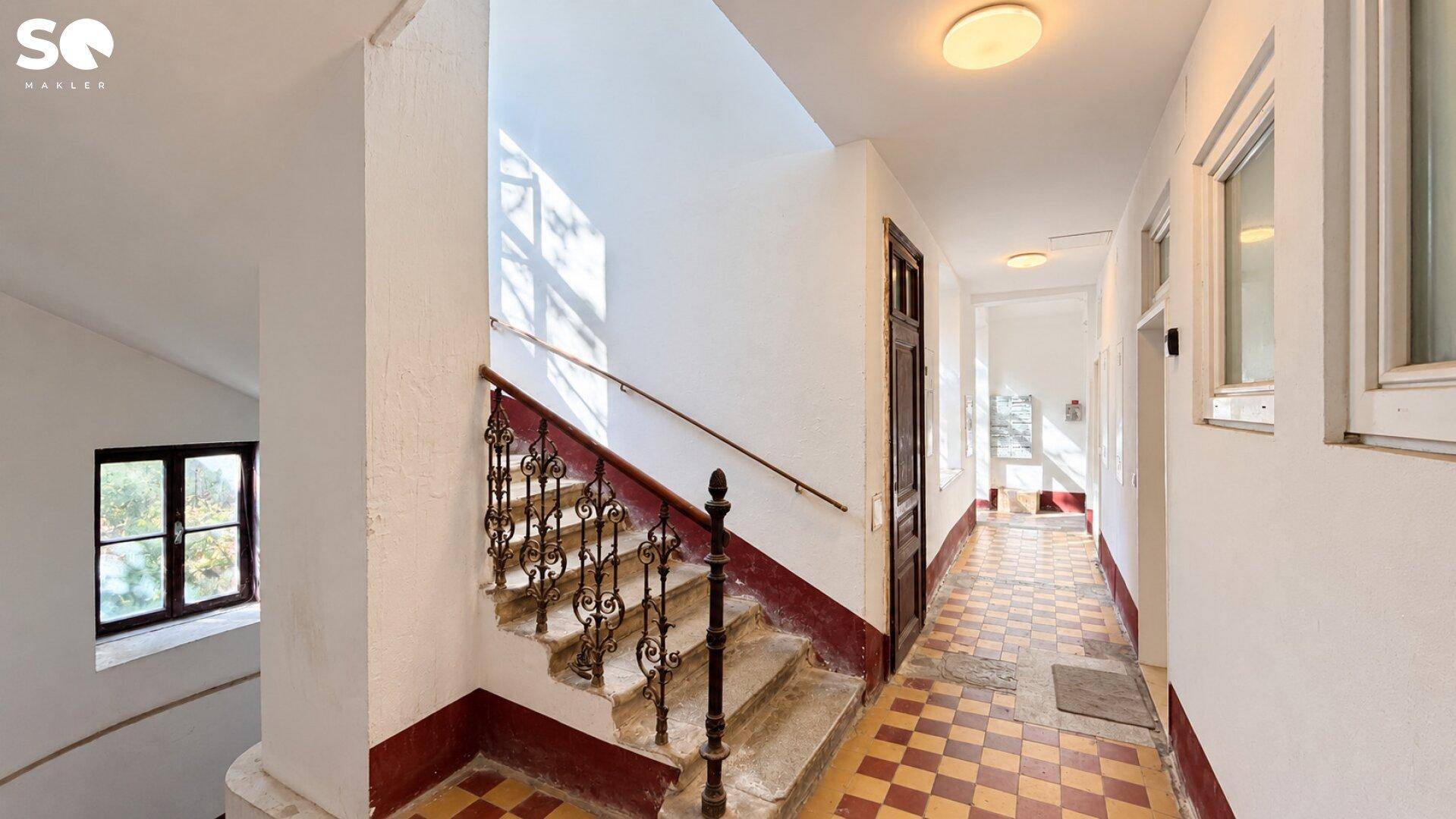 Helles Treppenhaus mit Tageslicht und traditionellem Geländer in einem Altbau.