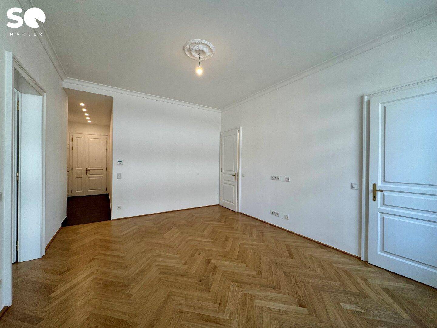 Geräumiger Flur mit Fischgrätparkett und Zugang zu verschiedenen Zimmern der Wohnung.