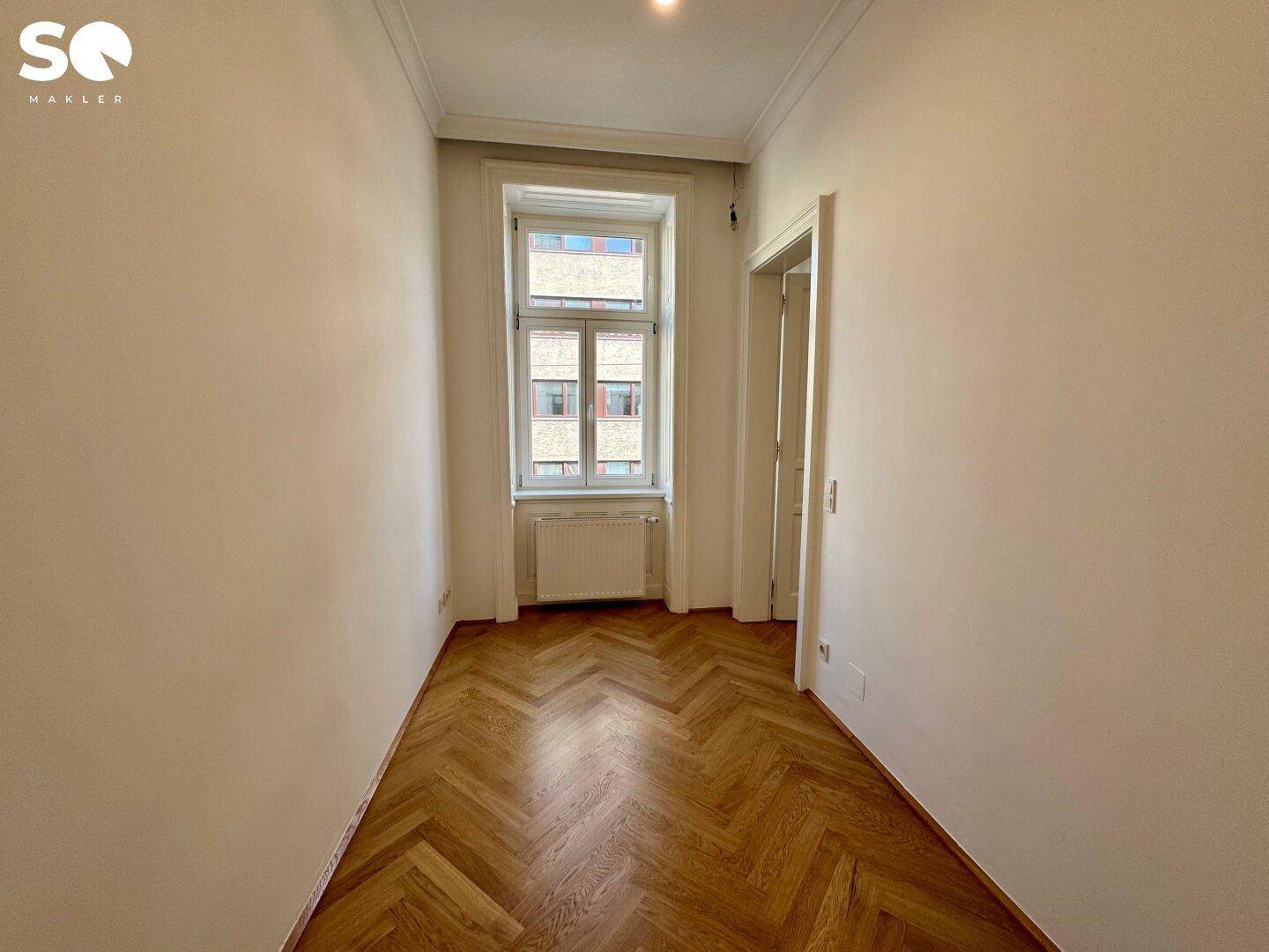 Gemütliches Zimmer mit Fischgrätparkett und einem Fenster, ideal als Schlaf- oder Arbeitsbereich.