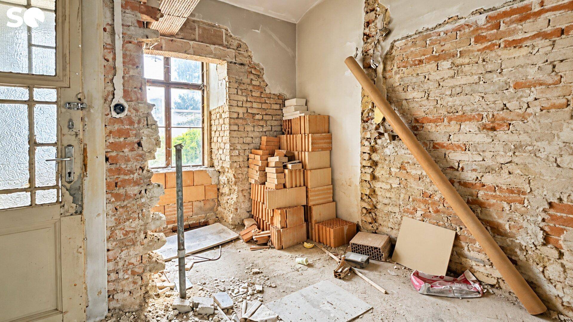 Renovierungsbedürftiger Raum mit freigelegten Ziegelwänden und Baumaterialien, bereit für den Umbau.