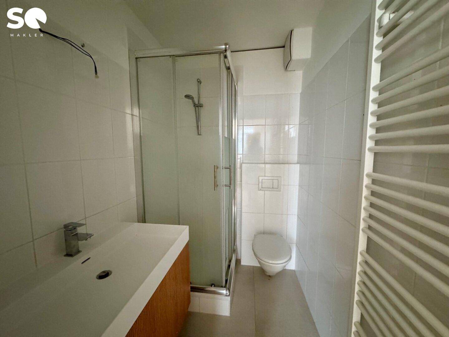 Modernes Badezimmer mit Duschkabine, Waschbecken und beheiztem Handtuchhalter.