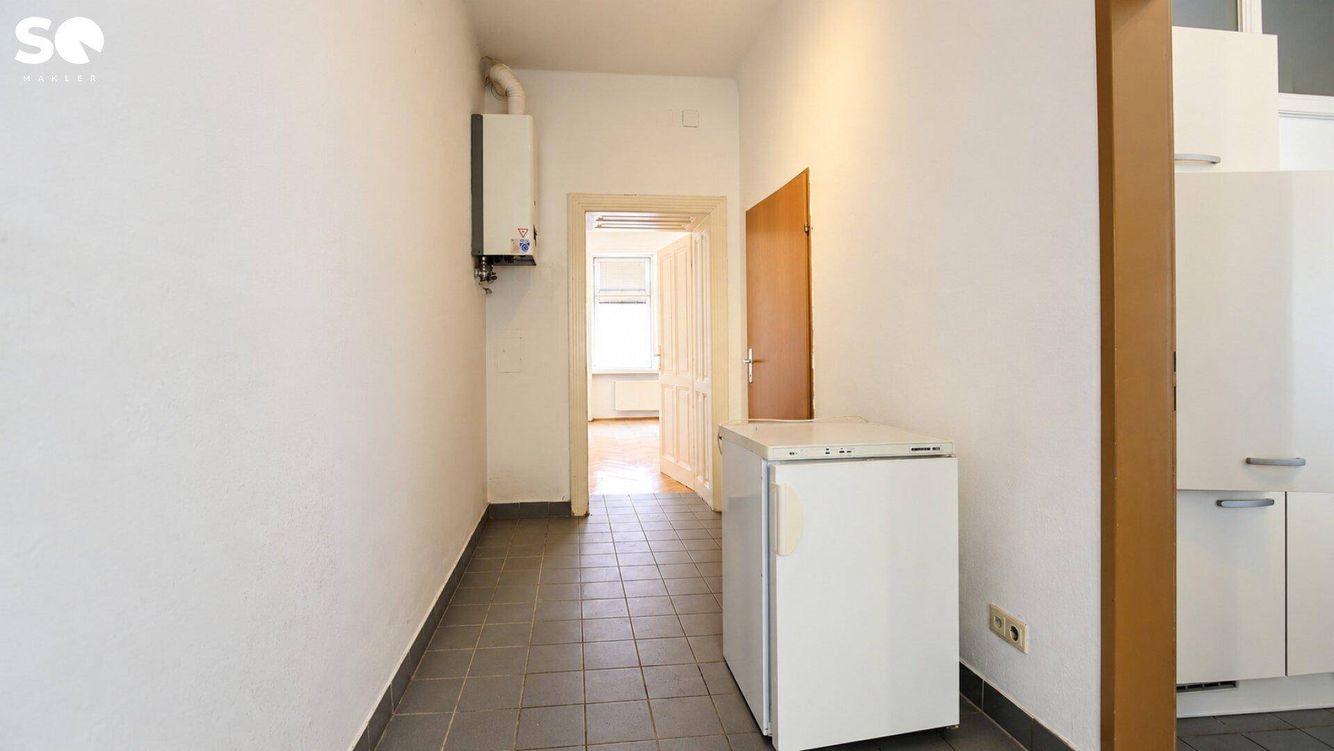 Heller Flur mit Fliesenboden und Blick in angrenzende Räume, ausgestattet mit einem Boiler.