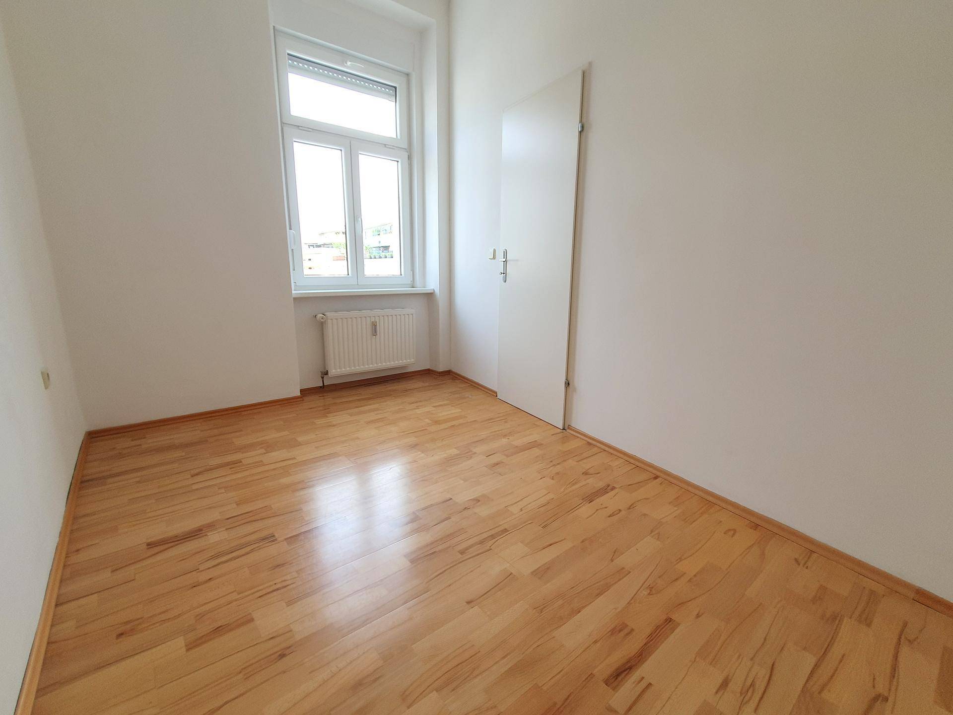 Kleineres, helles Zimmer mit Parkettboden und Fenster, ideal als Schlaf- oder Arbeitszimmer.