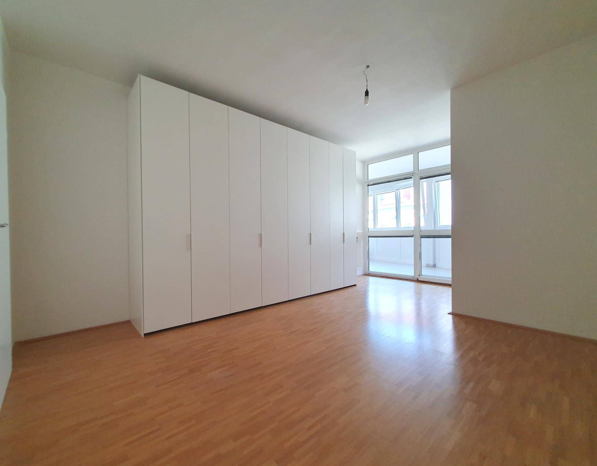Geräumiges Schlafzimmer mit Parkettboden und großem Einbauschrank, hell und funktional.