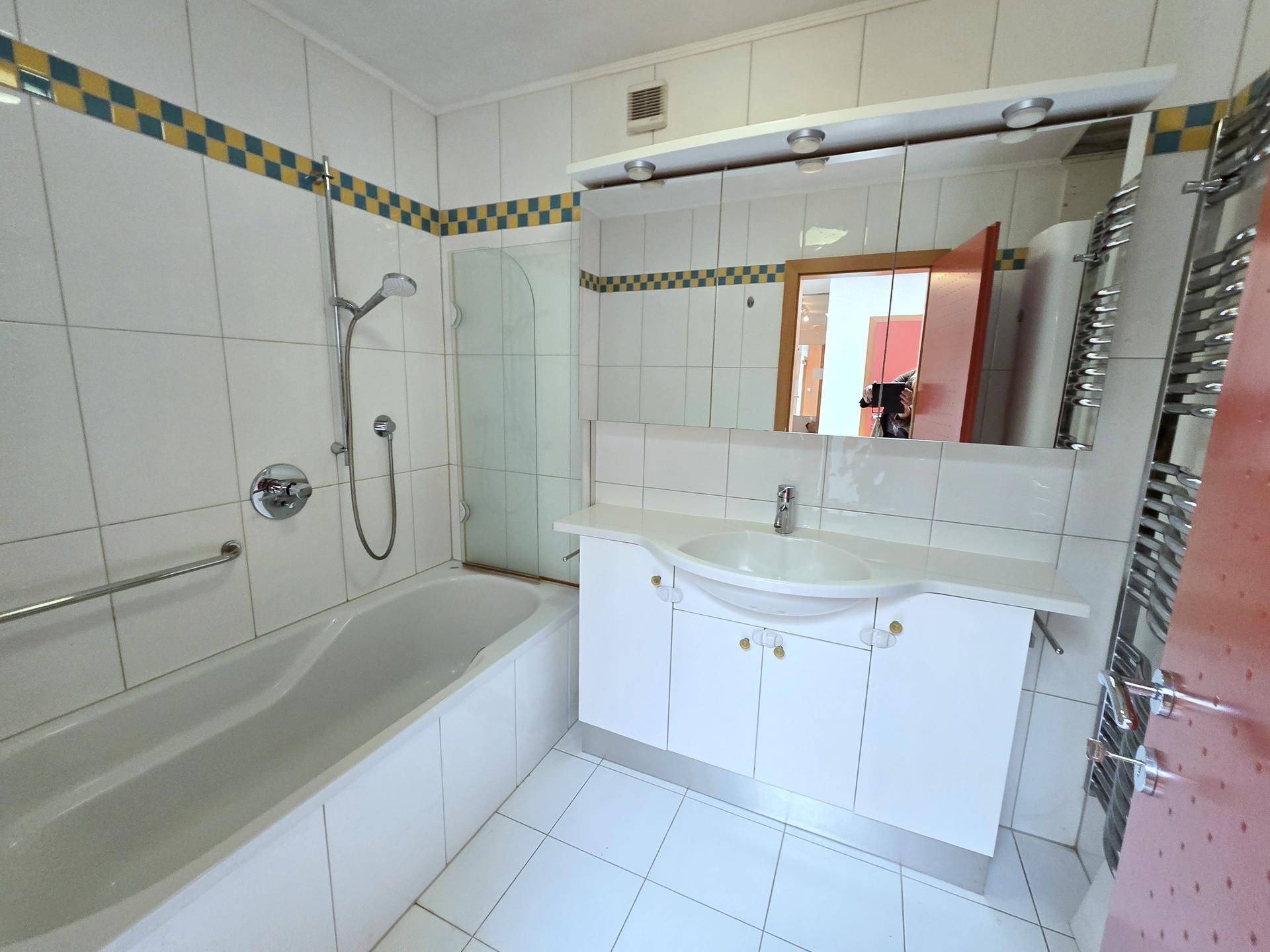 Helles Badezimmer mit Badewanne, Dusche und einem modernen Waschtisch mit Spiegelschrank.
