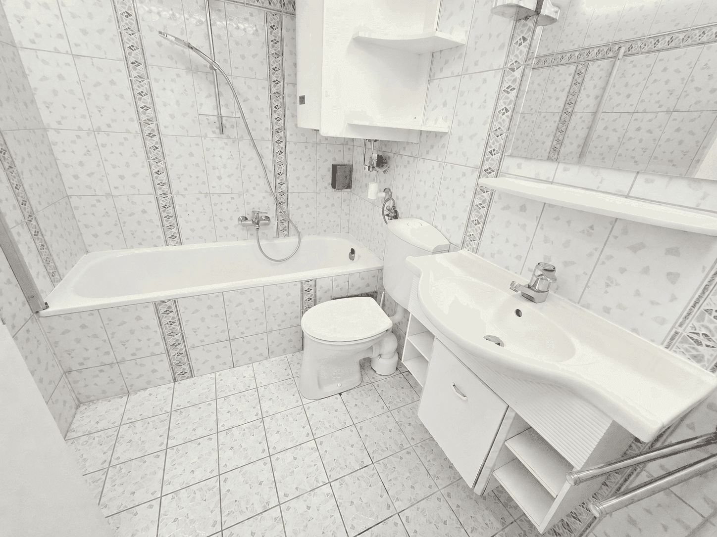 Funktionales Badezimmer mit Badewanne, Dusche, WC und Waschbecken, komplett gefliest in hellem Design.