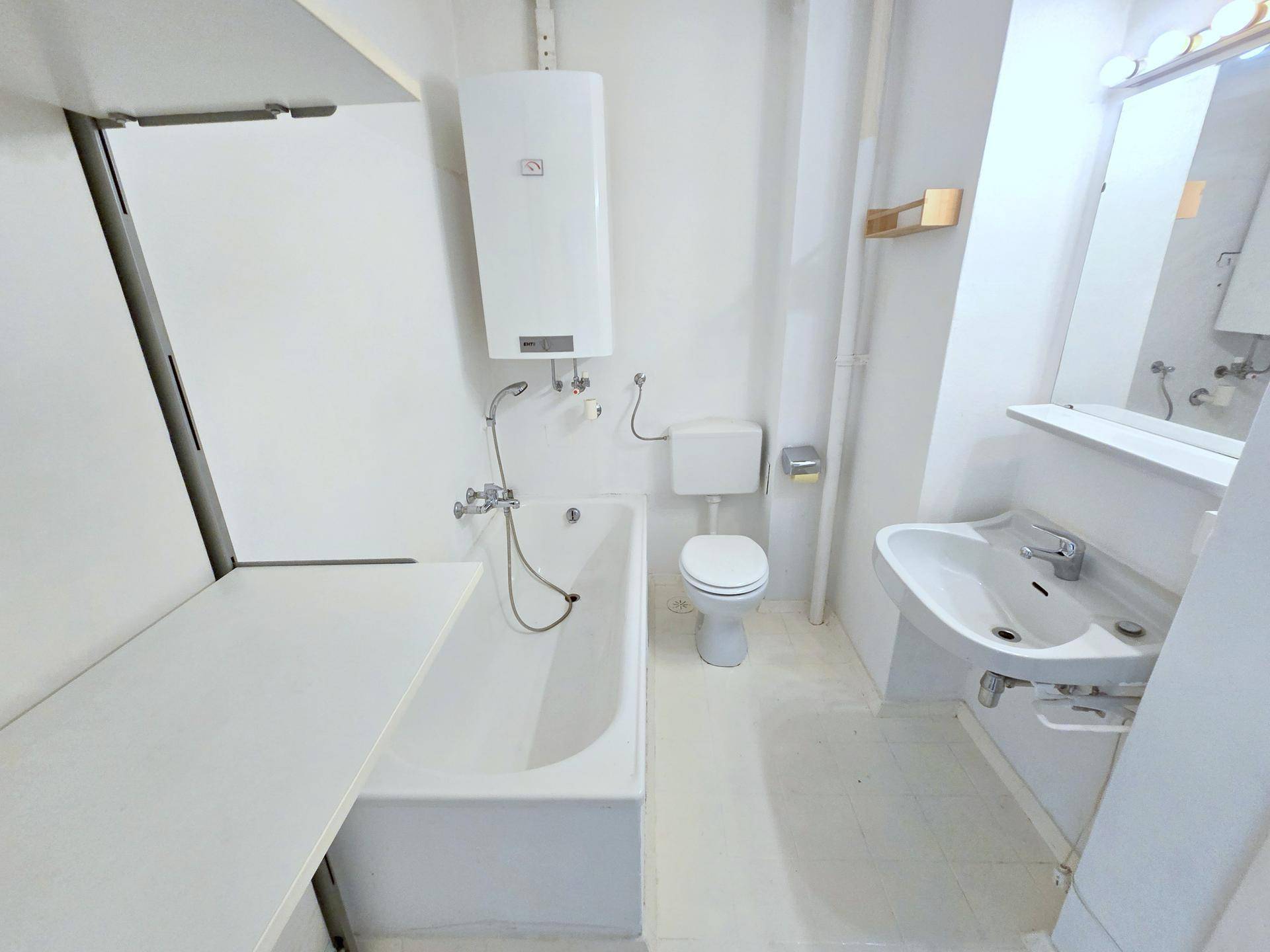 Helles Badezimmer mit Badewanne, WC und Waschbecken, ausgestattet mit einem Warmwasserboiler.