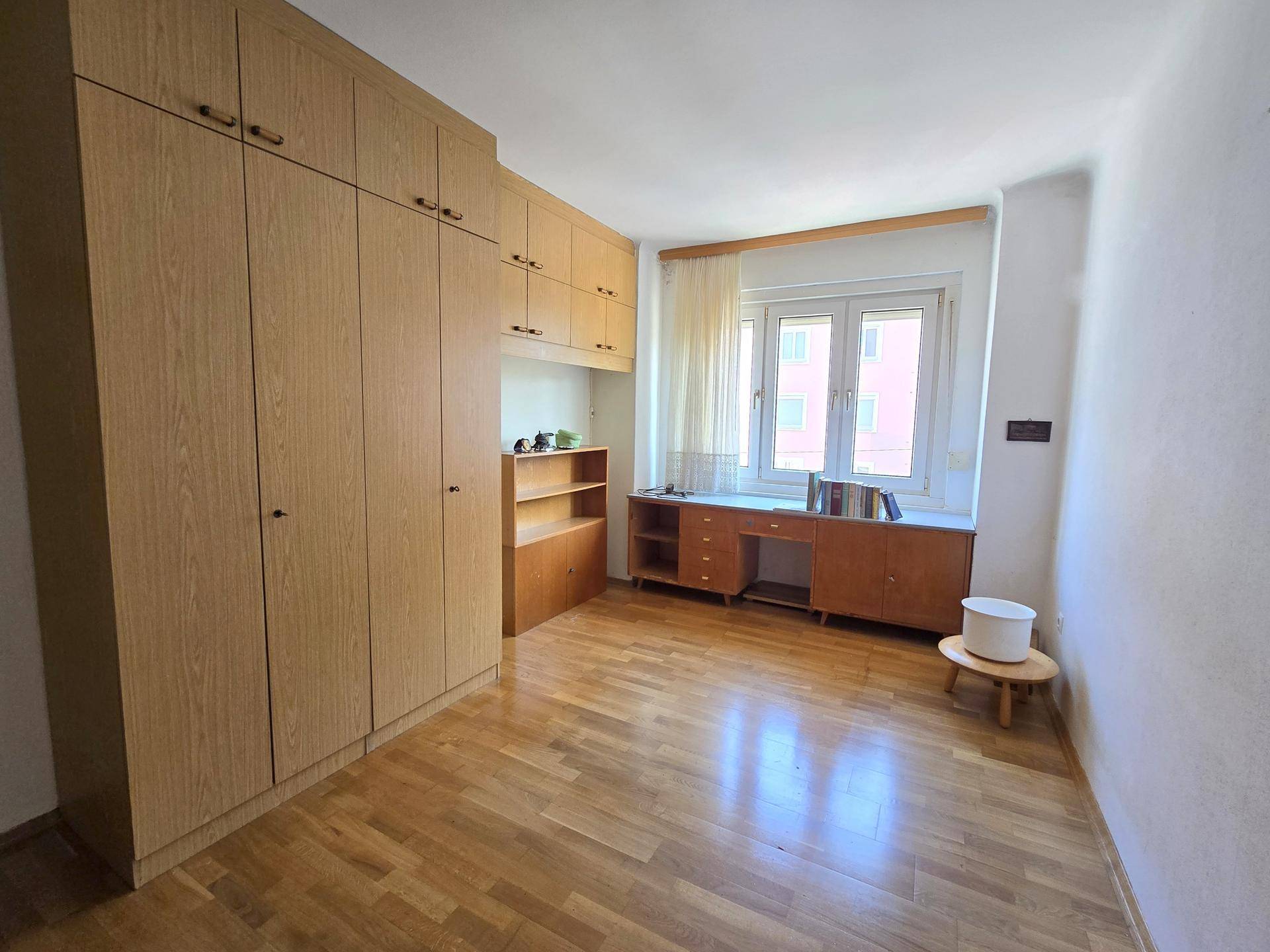 Helles Schlafzimmer mit Einbauschränken, Holzfußboden und Fenster.
