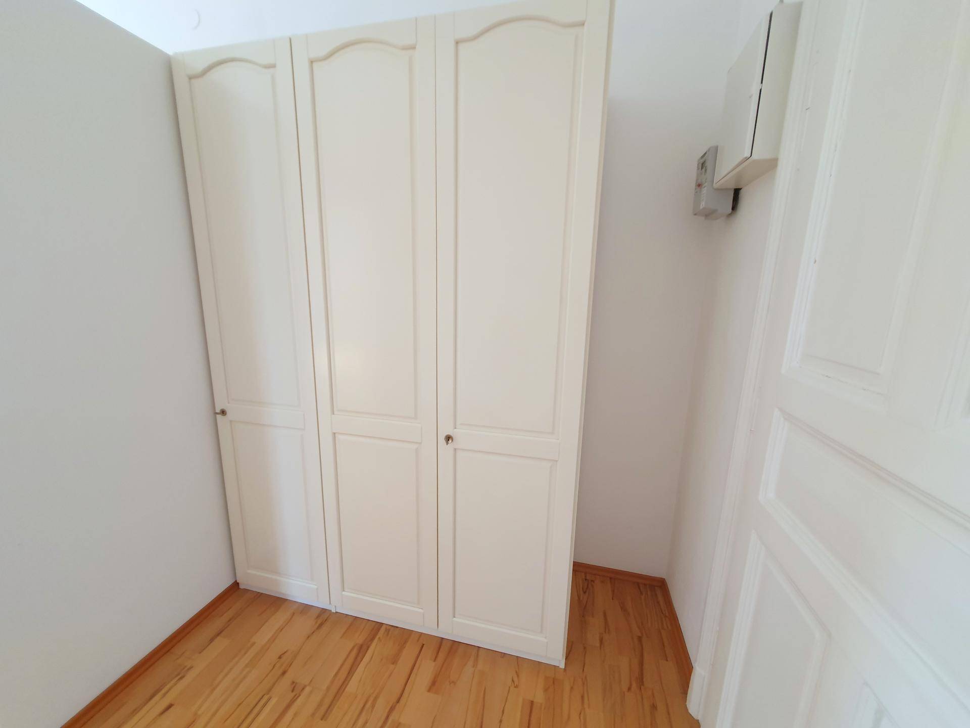 Kleiner Raum mit Einbauschrank und Parkettboden, geeignet als Ankleidezimmer oder Schlafzimmer.
